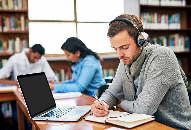 Students with laptops studying together in a library setting.